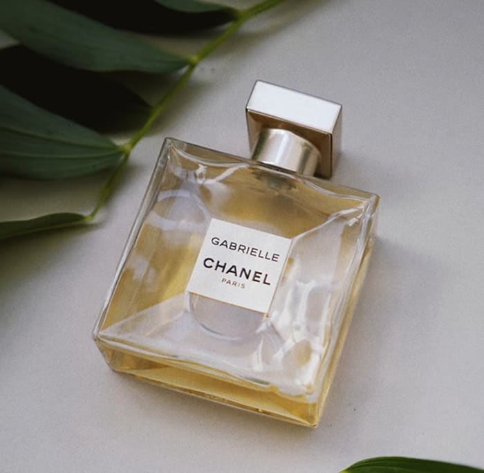 Squared-shaped glass bottle of Gabrielle CHANEL perfume, topped with a shimmering gold cap